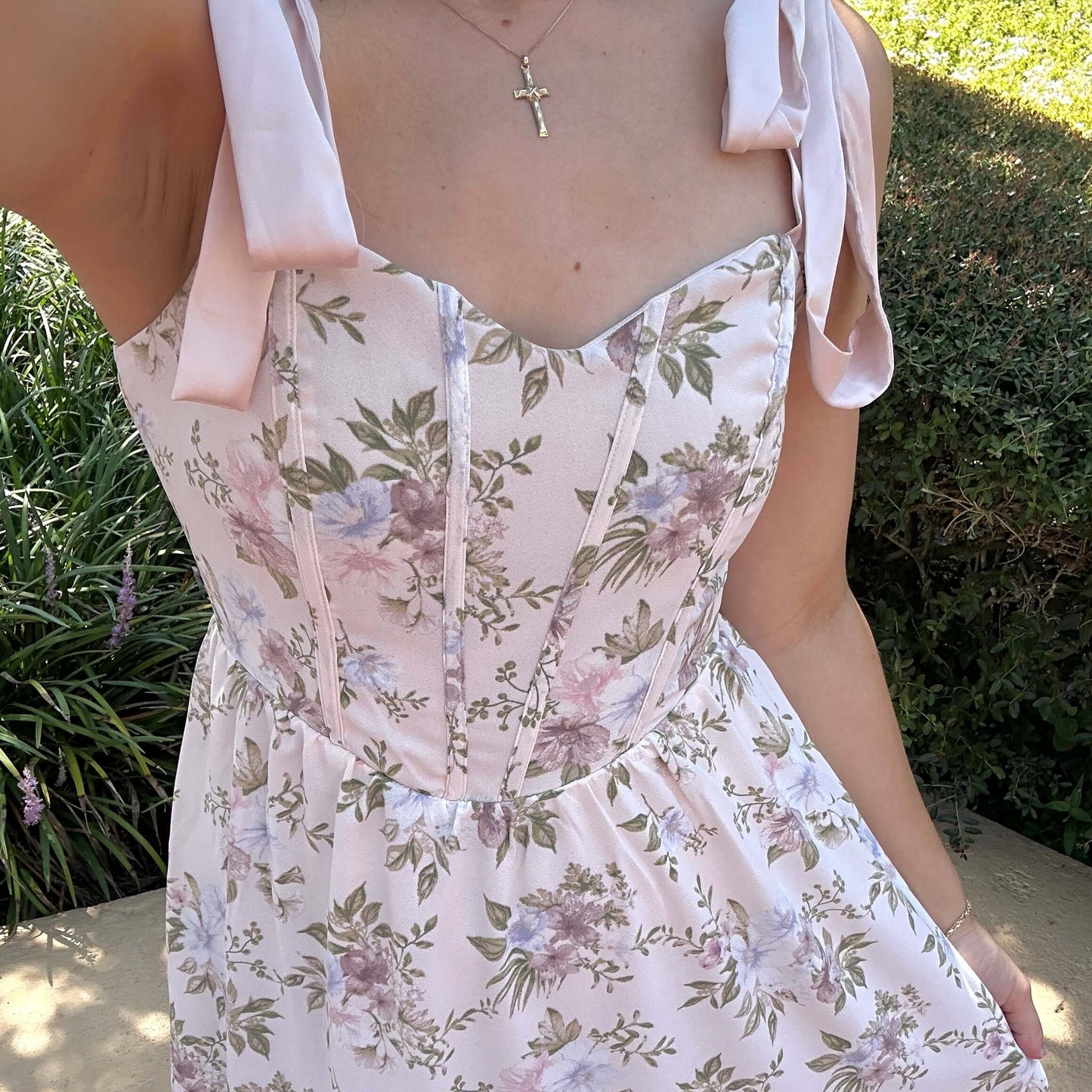 Woman wearing a floral dress with pink straps in an outdoor setting