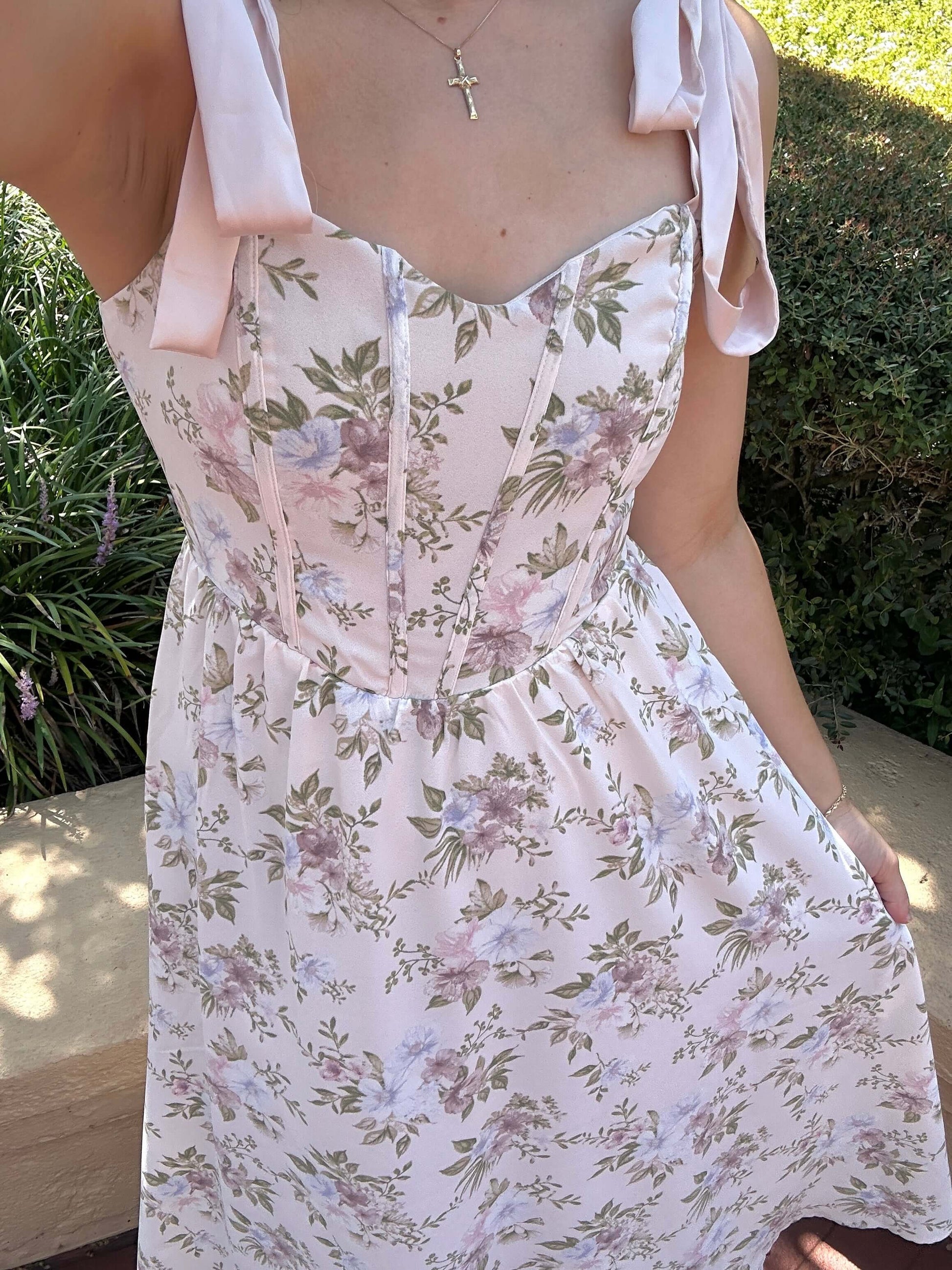 Woman wearing a floral dress with pink straps in an outdoor setting